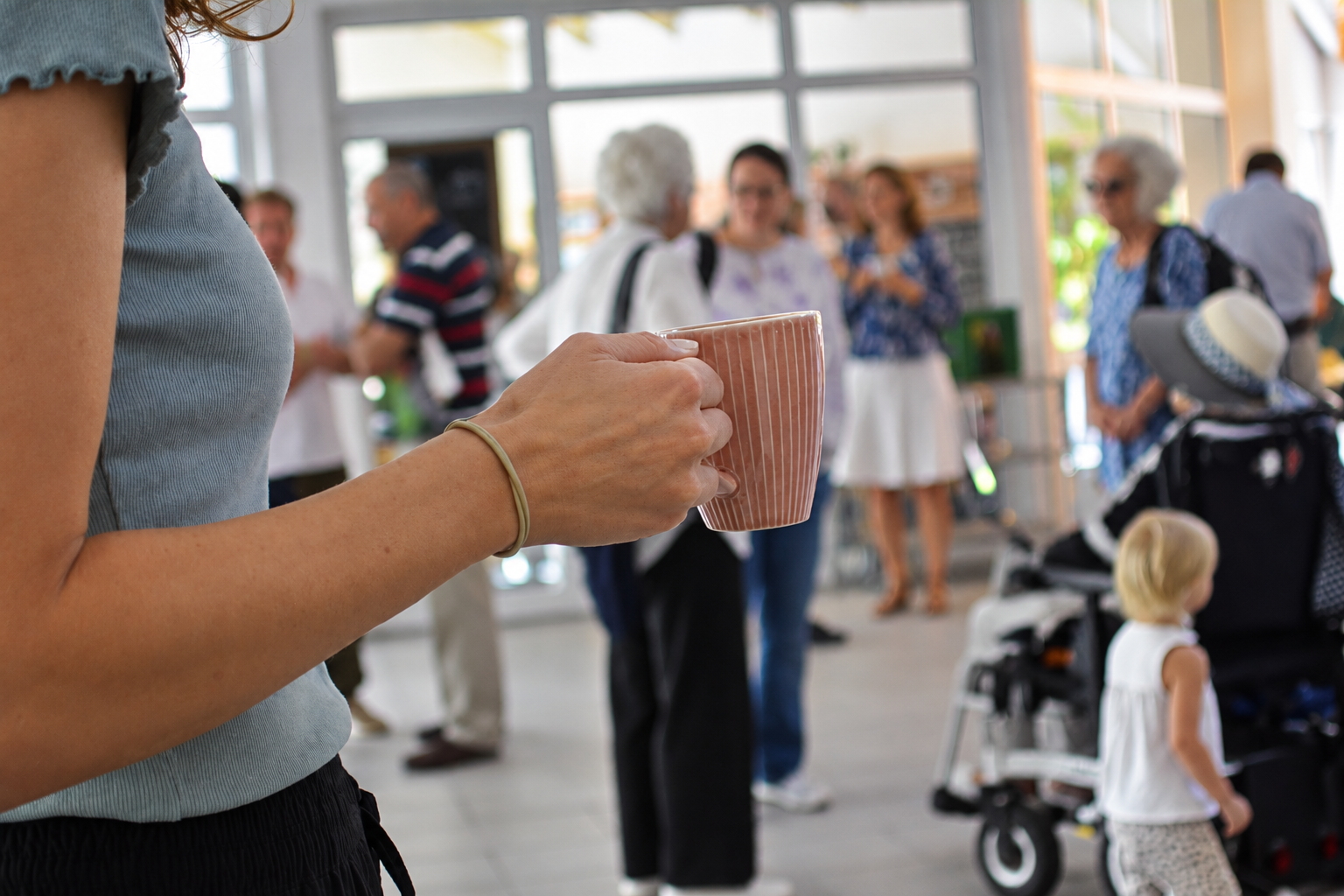 Kaffeetasse im Vordergrund, dahinter Menschen im Gespräch nach dem Gottesdienst